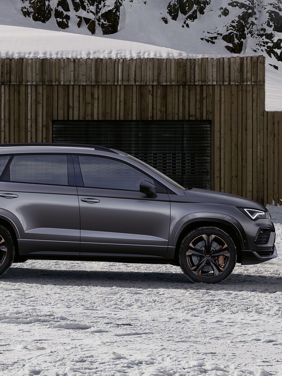 Ein CUPRA Ateca in grau, eine Frau steht davor