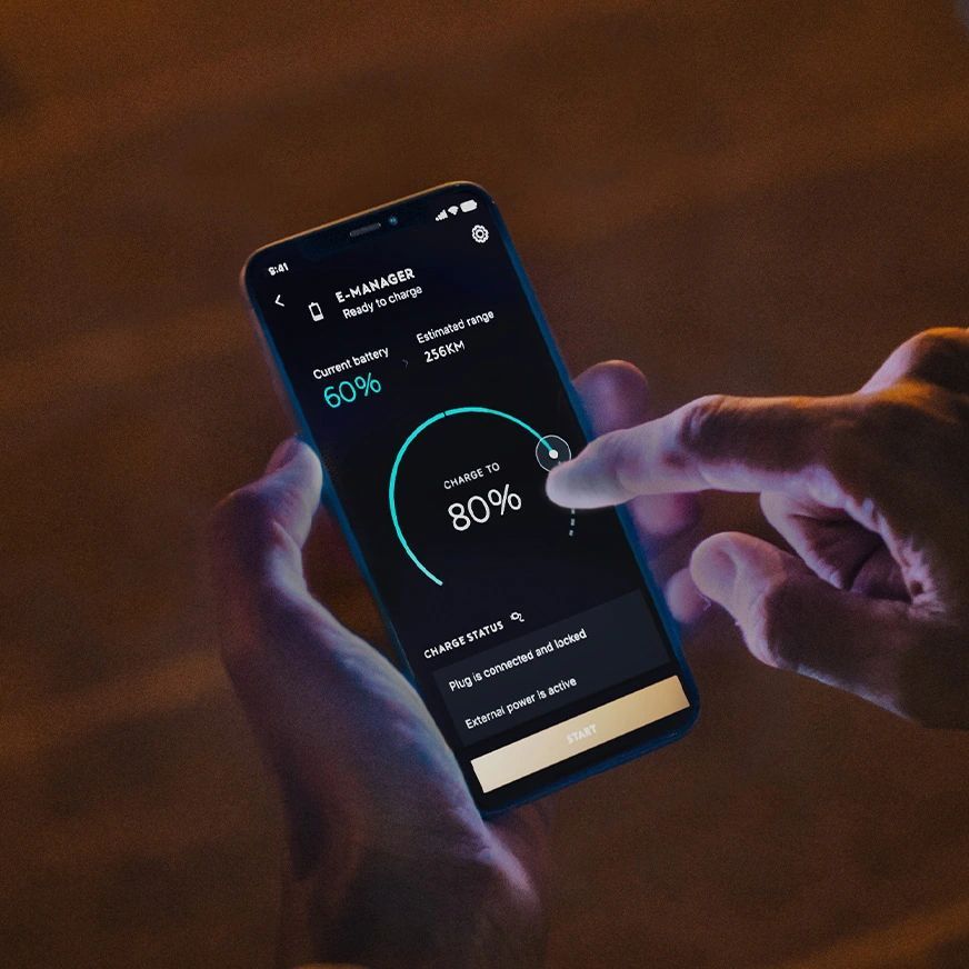Ruka drží smartfón s manažérom nabíjania. Na obrazovke je aplikácia, ktorá ukazuje stav batérie a možnosť zvýšenia výkonu z 60% na 80%. Pozadie je tmavé.