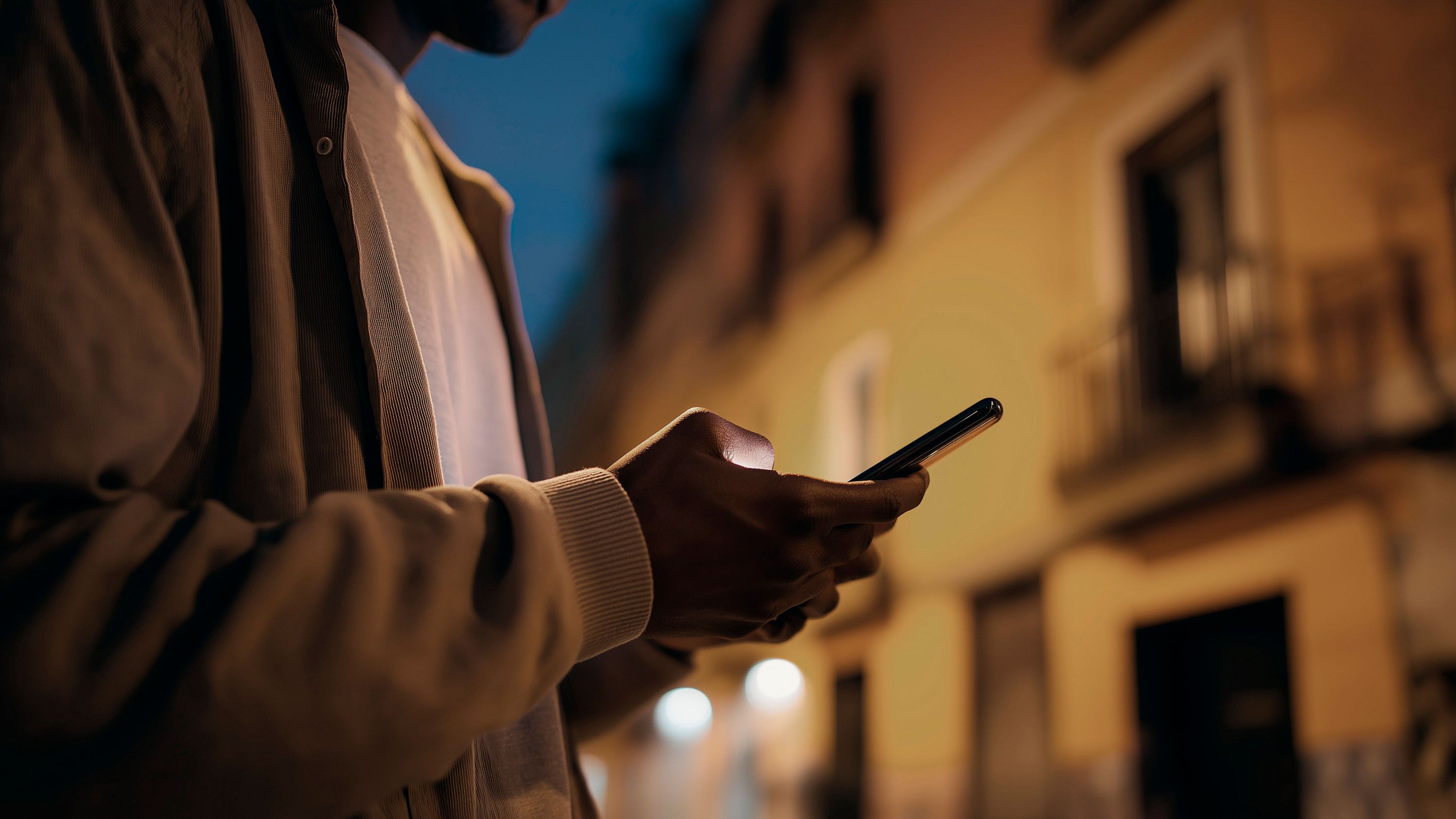 Detailný pohľad na muža, ktorý drží v rukách smartfón.