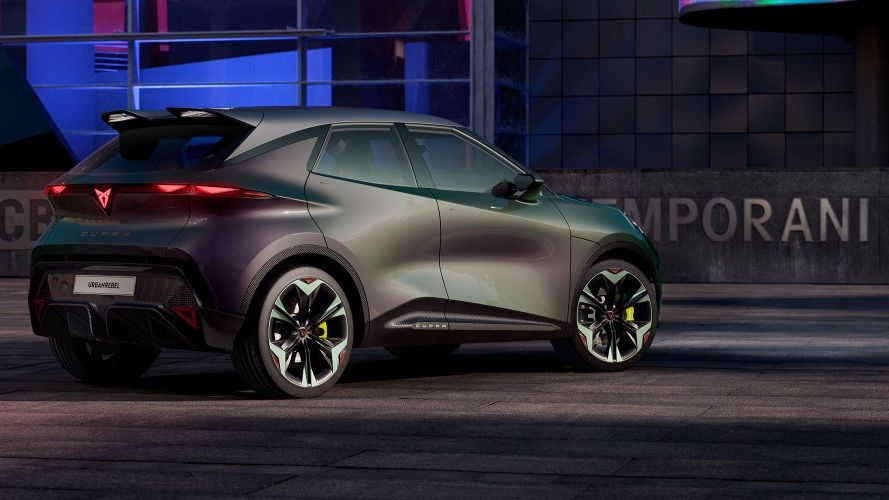 Moderné zelenofialové vozidlo s futuristickým dizajnom na nočnom mestskom parkovisku. V pozadí sú viditeľné neónové svetlá a budovy. Automobil má športové pneumatiky.