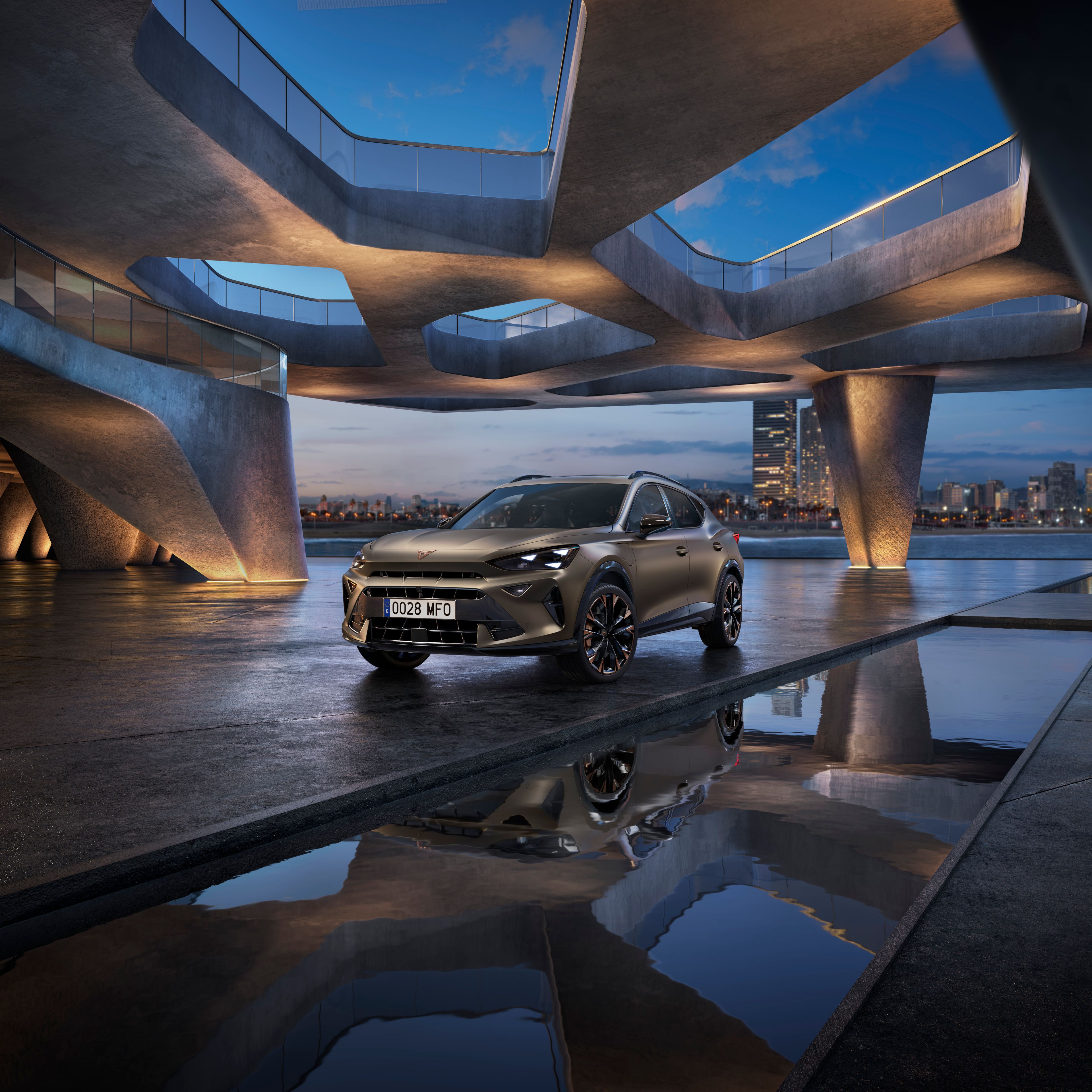 CUPRA Formentor stojí na ploche pri modernej stavbe pri mori,  za vozidlom vidieť mesto za súmraku.