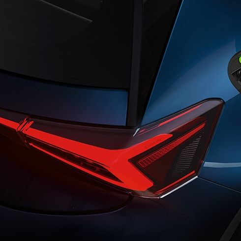 Elektrické SUV vozidlo modrej farby je nabíjané cez nabíjací kábel. Zadná časť vozidla je zvýraznená červeným svetlom. Nabíjací port svieti zeleným svetlom, čo značí nabíjanie.