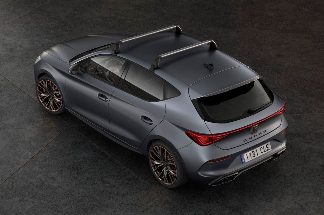 Pohľad na sivé športové auto CUPRA so strešným nosičom, ktoré je zaparkované na šedej dláždenej podlahe.