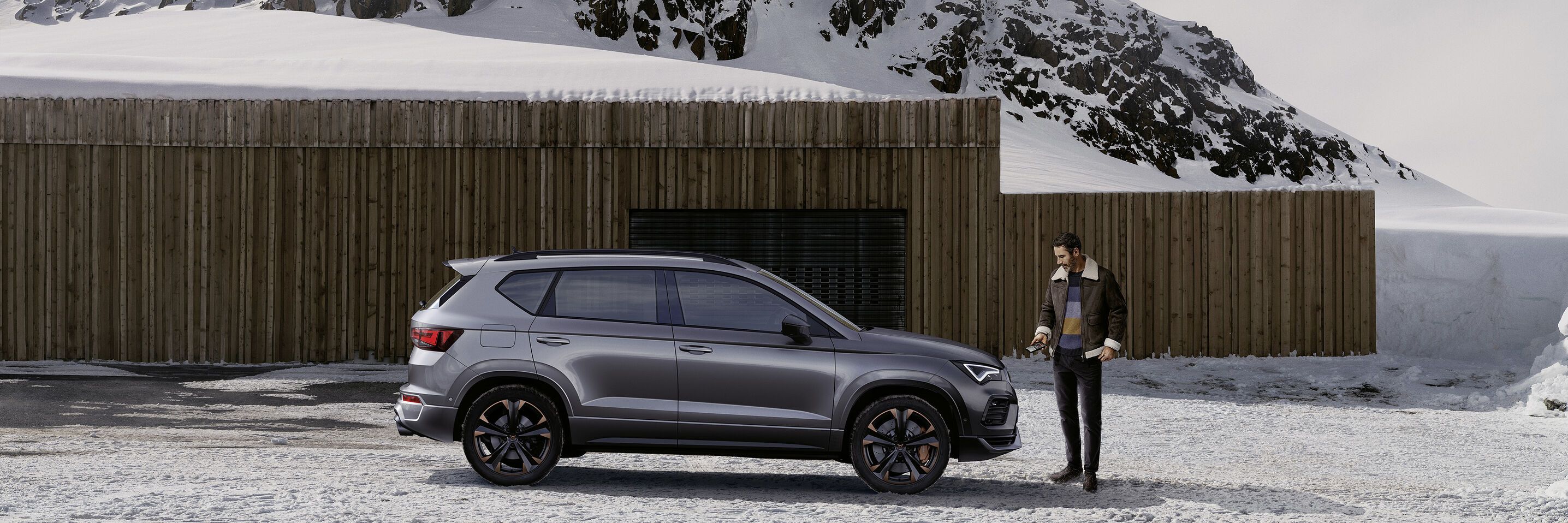 Ein CUPRA Ateca in grau, eine Frau steht davor