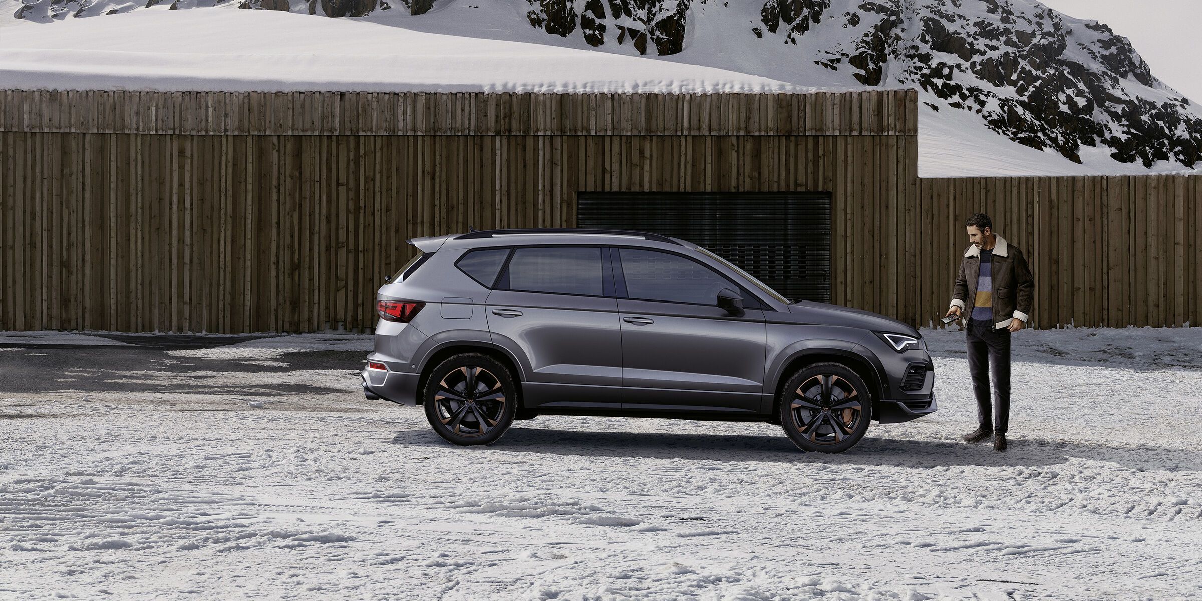 Ein CUPRA Ateca in grau, eine Frau steht davor