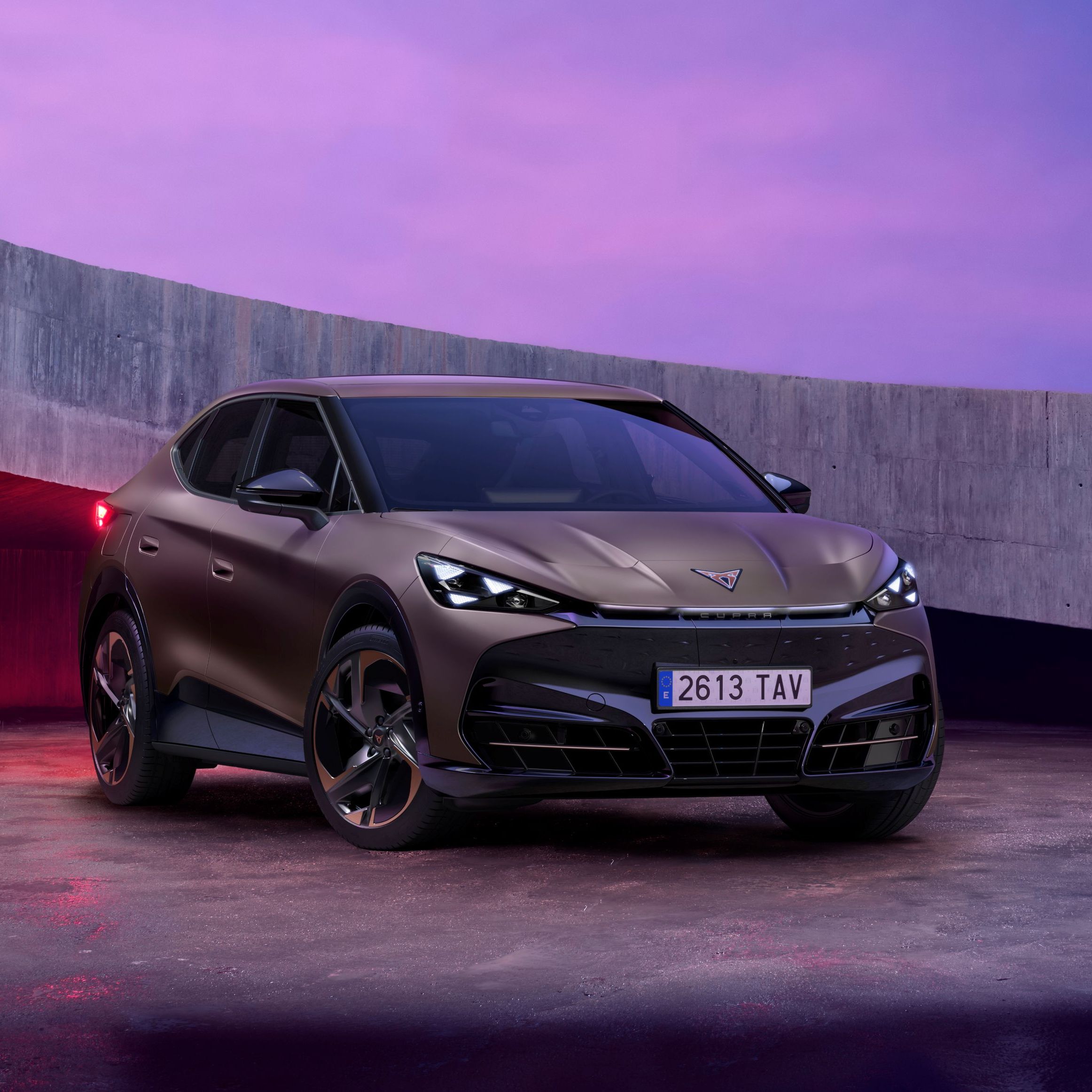 CUPRA Tavadcan zaparkovaný na betónovej ploche vedľa betónovej lávky. Obrázok dotvára ružový filter. 