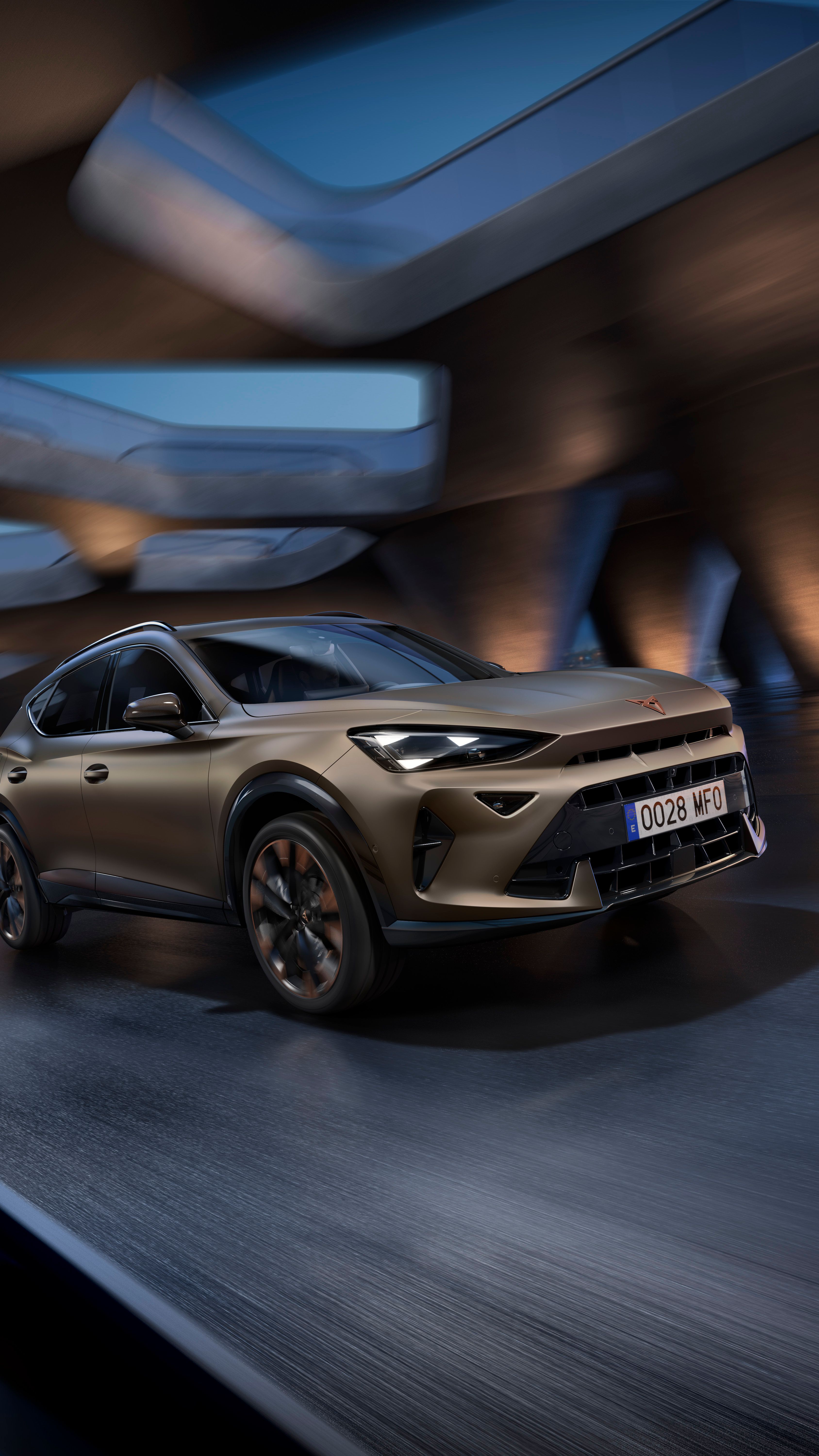 Moderné SUV auto jazdí po moste v noci, mestská panoráma viditeľná v diaľke. Auto je osvetlené reflektormi, ktoré zvýrazňujú jeho štýlový dizajn. Skyline mesta je rozmazaný, čo naznačuje vysokú rýchlosť vozidla.