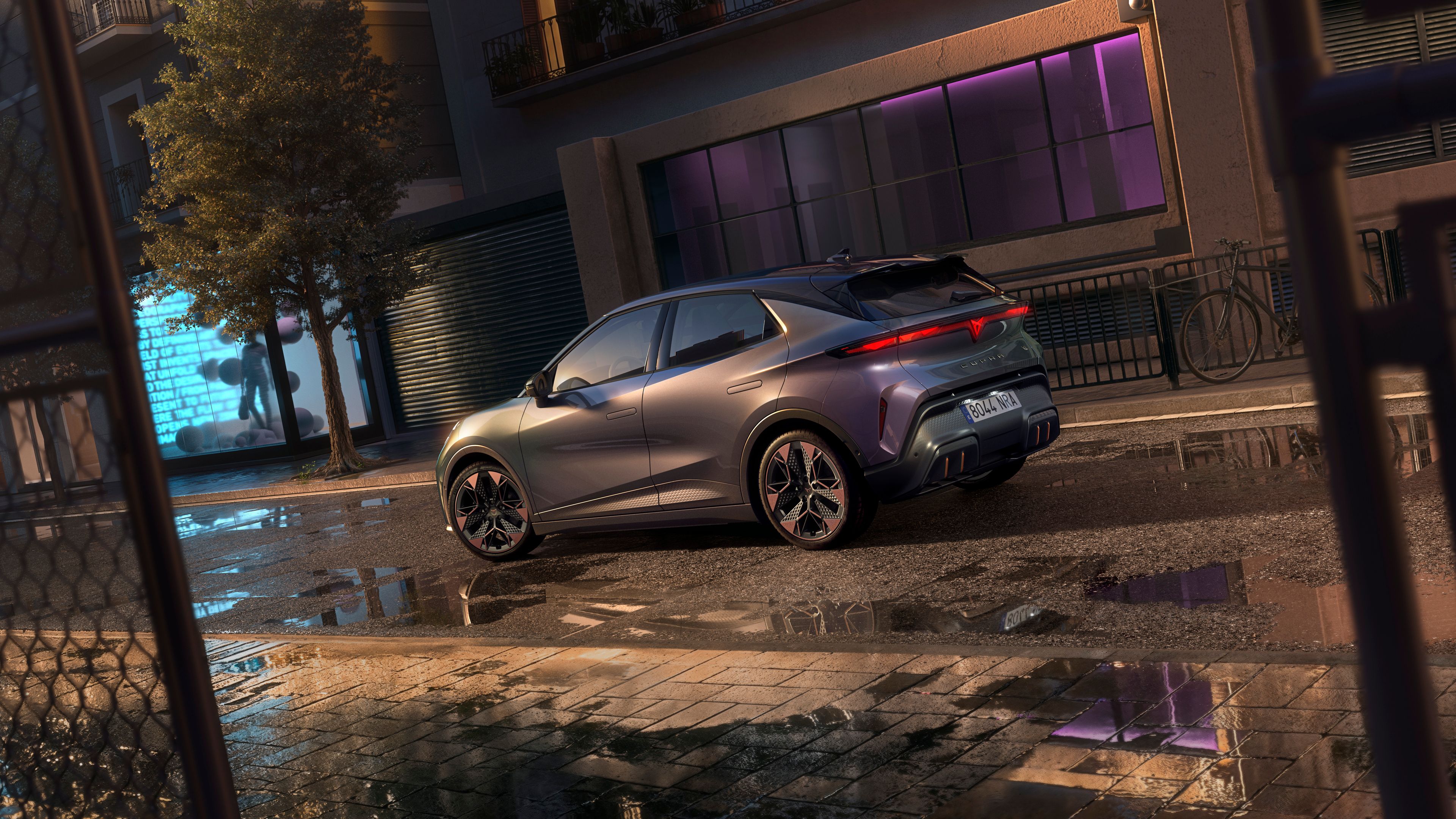 Detailný záber na zadné partie vozidla CUPRA Raval VZ v odtieni Plasma s 19-palcovými diskami, ktorý je zaparkovaný na mestskej ulici v noci.